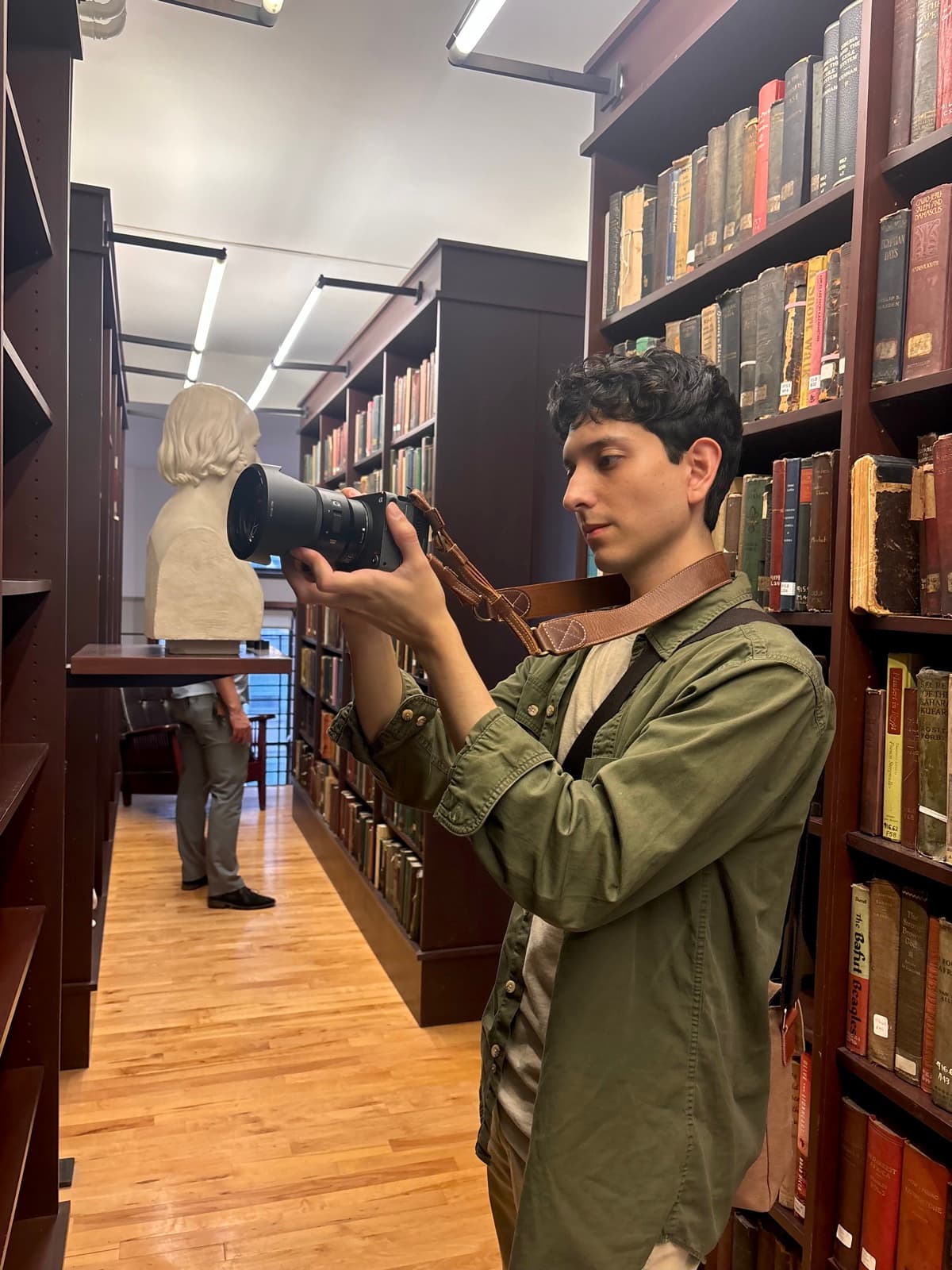 Esteban Saavedra holding his camera in a library